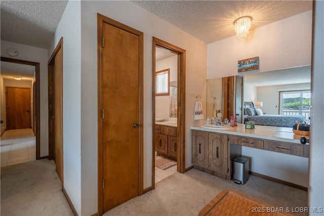 bathroom with a textured ceiling, vanity, and baseboards