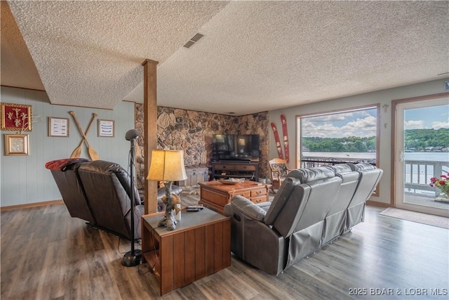 living area with wood finished floors, plenty of natural light, a textured ceiling, and baseboards