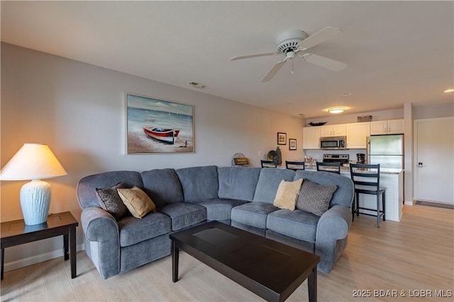 living area featuring light wood-style flooring and a ceiling fan