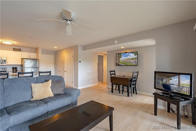 living room featuring light wood-style floors, baseboards, ceiling fan, and recessed lighting
