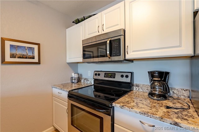 kitchen featuring appliances with stainless steel finishes, white cabinets, and light stone countertops