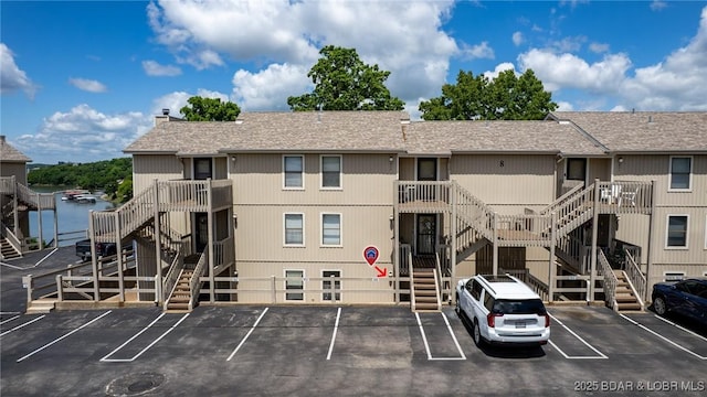 view of building exterior featuring stairway and uncovered parking