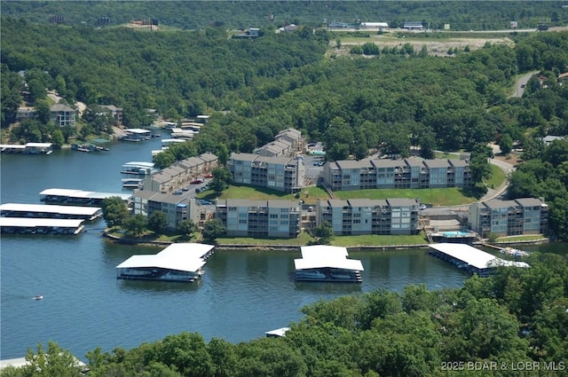 drone / aerial view of a nearby body of water and a forest