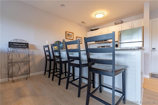 dining area featuring light wood-style flooring and baseboards