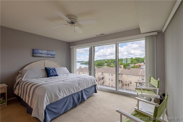 carpeted bedroom featuring a water view, access to exterior, and ceiling fan