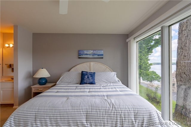 bedroom featuring ensuite bath, a water view, and ceiling fan