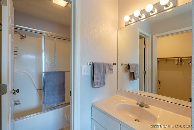 bathroom featuring vanity, toilet, bath / shower combo with glass door, and a walk in closet