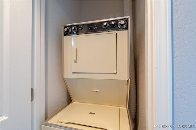 washroom with stacked washing machine and dryer and a textured wall