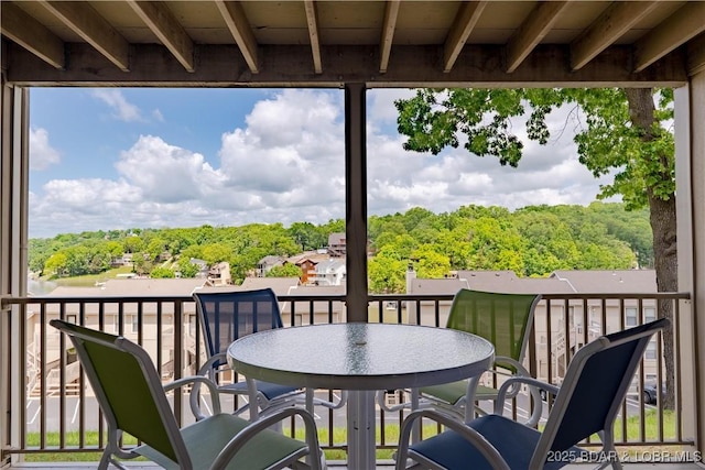 balcony with outdoor dining area and a wooded view