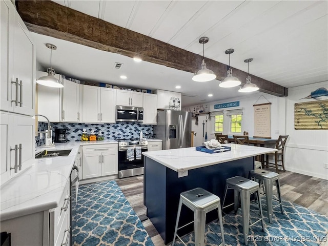 kitchen featuring appliances with stainless steel finishes, dark wood-style floors, a sink, beam ceiling, and light stone countertops