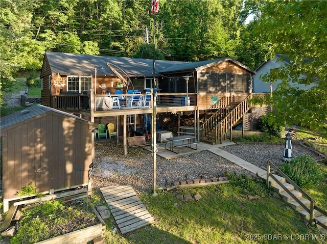 back of property with a storage unit, stairway, a patio, an outdoor structure, and a deck