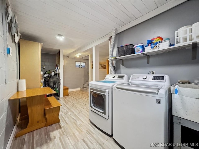 washroom with separate washer and dryer, concrete block wall, and light wood finished floors