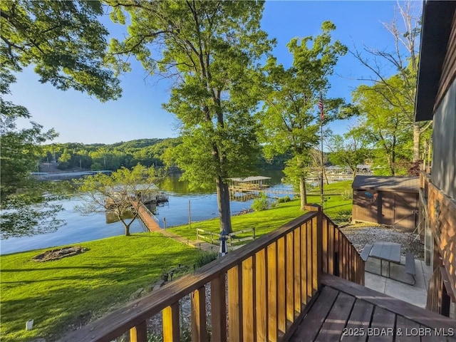 wooden deck featuring a water view and a lawn