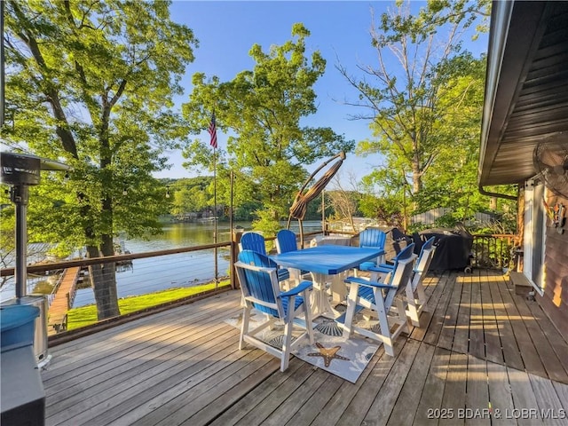 wooden terrace with a water view and outdoor dining space