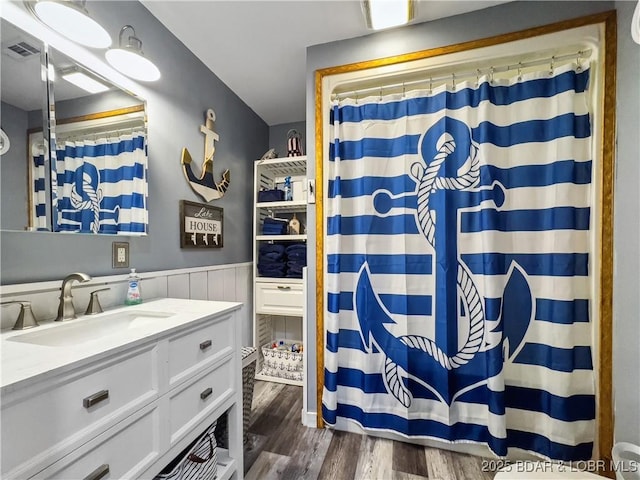 full bathroom with wood finished floors, a wainscoted wall, vanity, and a shower with curtain