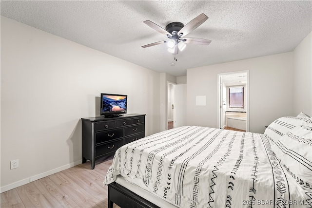 bedroom featuring light wood finished floors, baseboards, a textured ceiling, ceiling fan, and ensuite bath