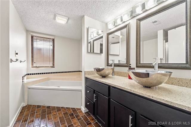 full bathroom featuring a bath, double vanity, a textured ceiling, and baseboards