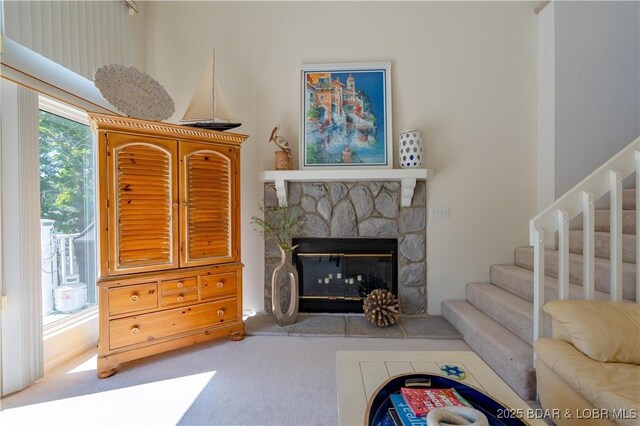 carpeted living area with a fireplace and stairs