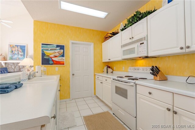 kitchen featuring white appliances, white cabinets, light countertops, light tile patterned flooring, and a sink