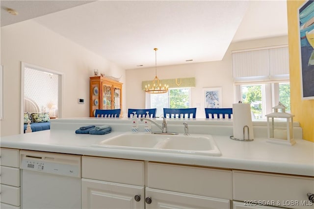 kitchen featuring white dishwasher, a sink, light countertops, and a chandelier