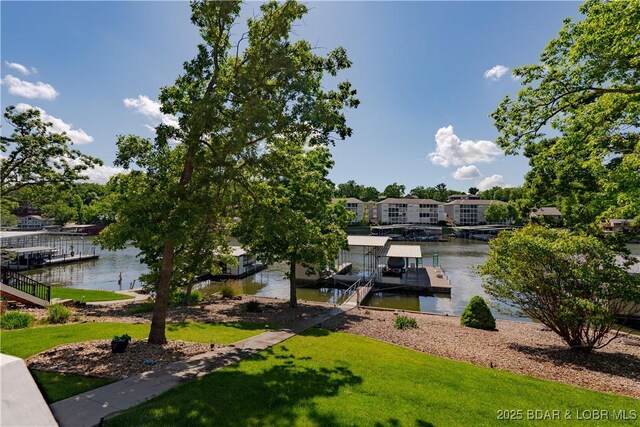 dock area with a water view, boat lift, and a yard