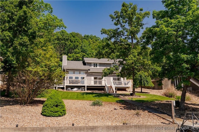 rear view of property featuring a deck, a chimney, and a yard