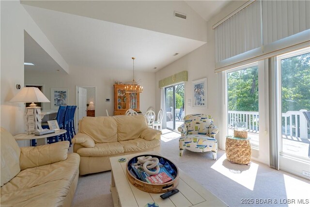 carpeted living area with a chandelier and vaulted ceiling