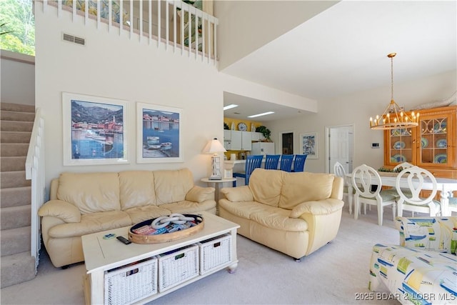 living room with stairs, a chandelier, and light carpet
