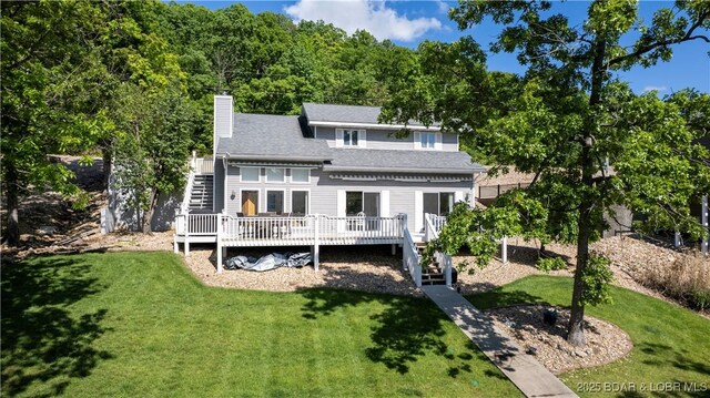 back of property with stairs, a deck, a lawn, and a chimney