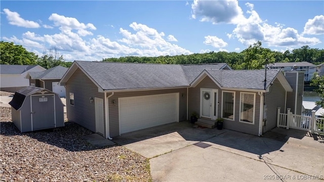 ranch-style home with an attached garage, a storage shed, concrete driveway, and a shingled roof
