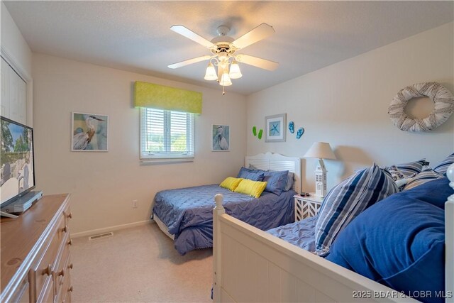 bedroom with light carpet, a ceiling fan, and baseboards