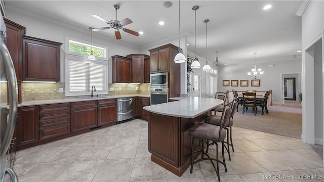 kitchen with appliances with stainless steel finishes, a sink, light tile patterned floors, a kitchen breakfast bar, and a ceiling fan