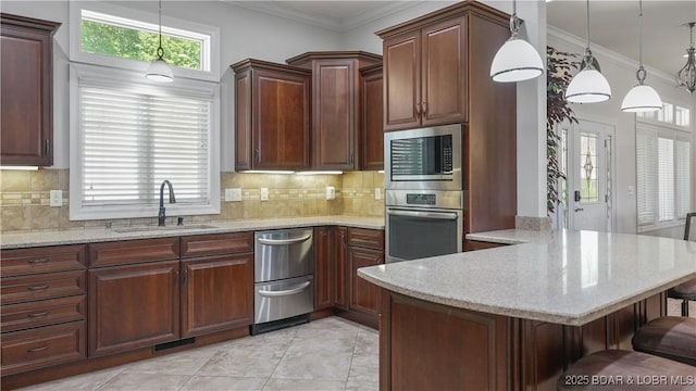 kitchen featuring stainless steel appliances, a sink, a breakfast bar, a peninsula, and pendant lighting