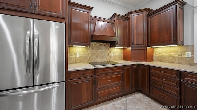 kitchen with freestanding refrigerator, black electric cooktop, crown molding, light stone counters, and decorative backsplash