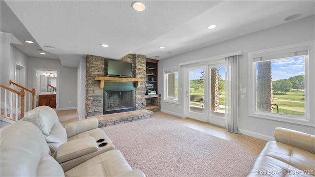 carpeted living area featuring baseboards, built in shelves, stairway, a stone fireplace, and recessed lighting