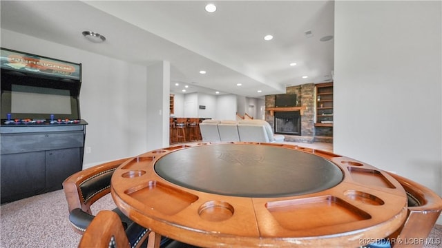 rec room with a stone fireplace, recessed lighting, and built in features