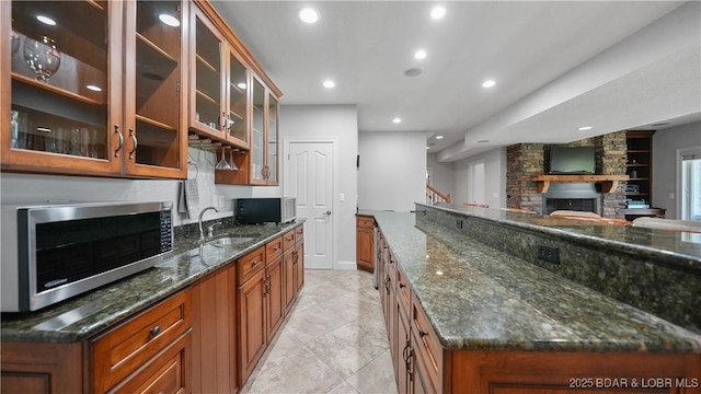 kitchen featuring stainless steel microwave, a sink, brown cabinets, and recessed lighting