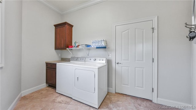 laundry room featuring crown molding, washer and dryer, cabinet space, and baseboards