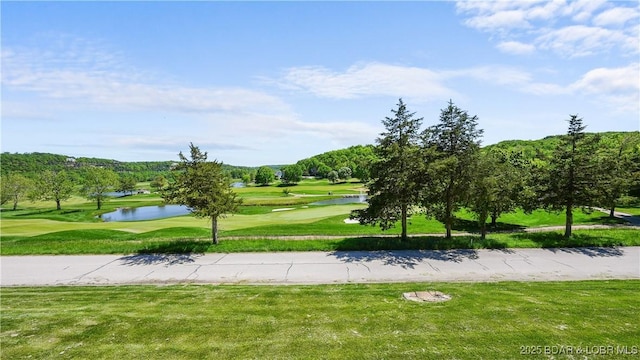 view of home's community with golf course view, a water view, and a yard
