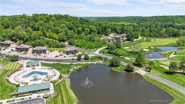 drone / aerial view of a nearby body of water, a local golf course, and a forest