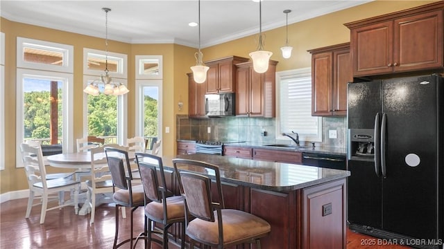 kitchen featuring black appliances, a sink, a kitchen bar, a center island, and tasteful backsplash