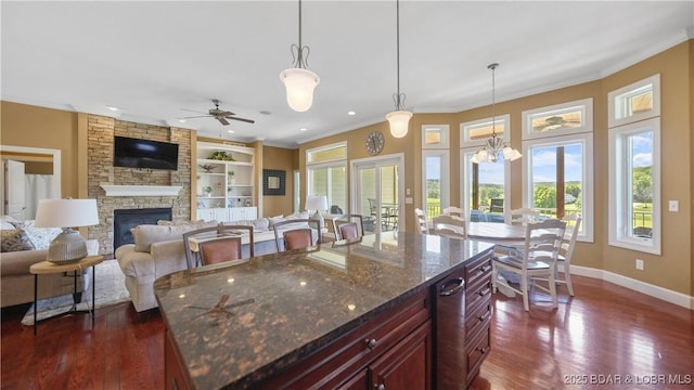 kitchen featuring reddish brown cabinets, ornamental molding, a fireplace, dark wood-style flooring, and baseboards