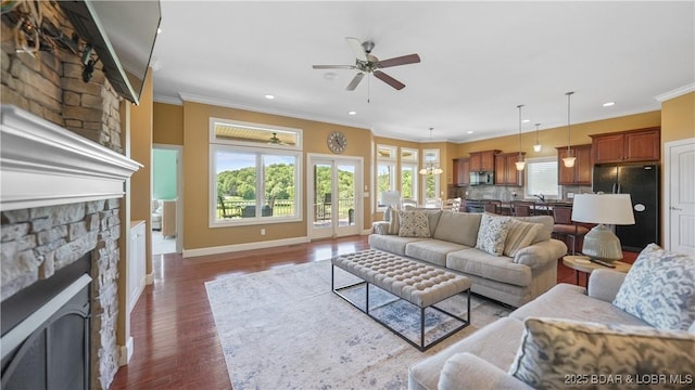living room featuring a fireplace, ceiling fan, ornamental molding, wood finished floors, and recessed lighting