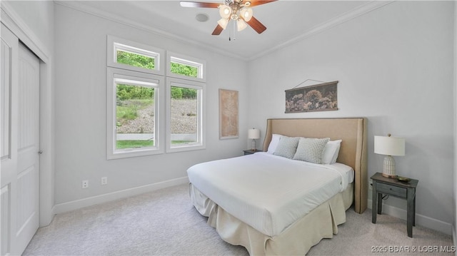 carpeted bedroom with baseboards, ornamental molding, a closet, and a ceiling fan