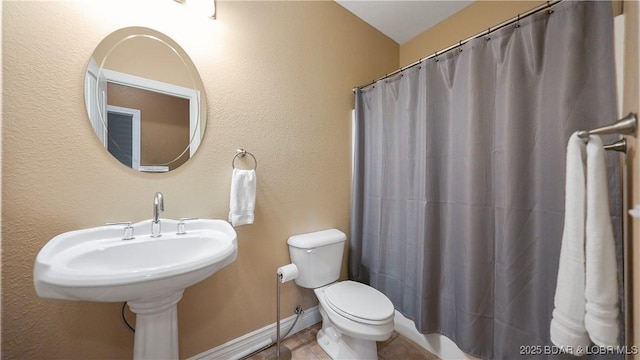 bathroom with toilet, tile patterned flooring, curtained shower, and baseboards
