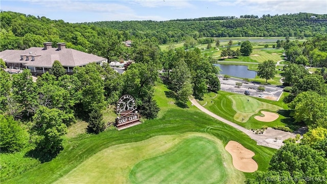 bird's eye view of a nearby body of water, a golf course, and a heavily wooded area