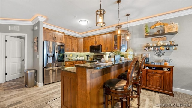 kitchen featuring appliances with stainless steel finishes, crown molding, brown cabinets, a peninsula, and tasteful backsplash