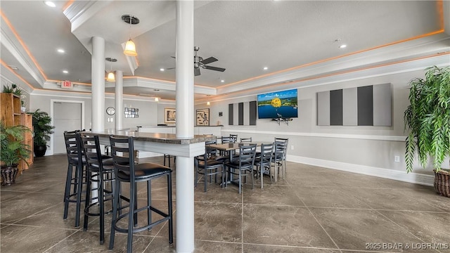 kitchen featuring a raised ceiling, decorative columns, crown molding, ceiling fan, and a kitchen island