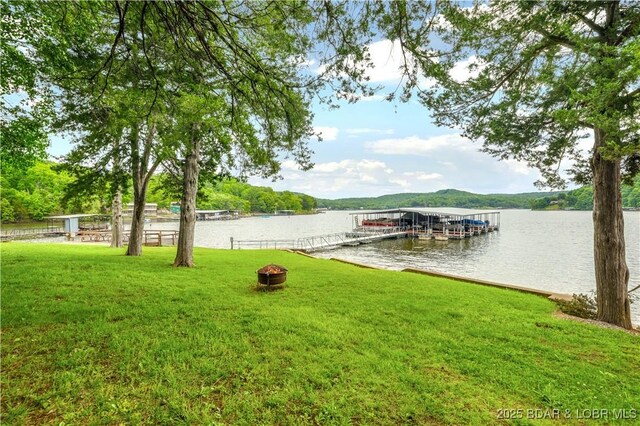 424 Bowers Dr, Camdenton, MO 65020 - view of green lawn featuring a boat dock, a water view, boat lift, and an outdoor fire pit