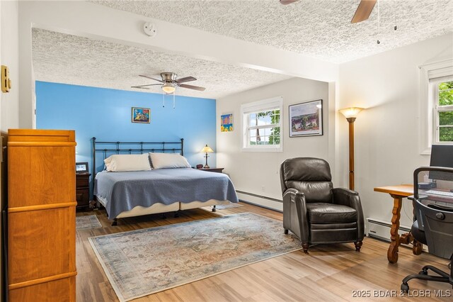 12 Mimosa Rd, Rocky Mount, MO 65072 - bedroom with baseboard heating, a textured ceiling, multiple windows, and wood finished floors